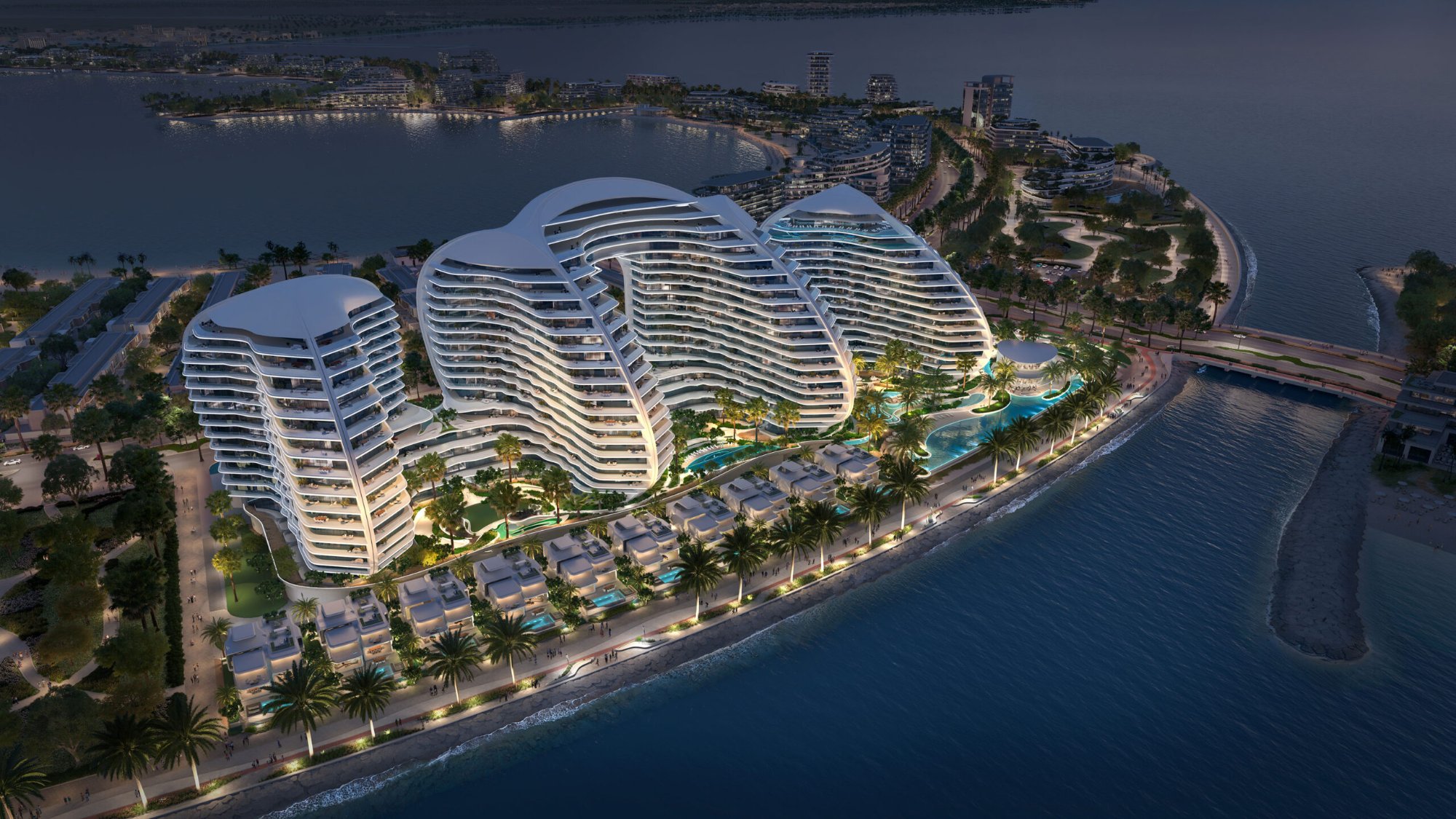 Oystra aerial night render — three biomorphic towers illuminated against the Al Marjan Island night skyline, pool decks and promenade visible below